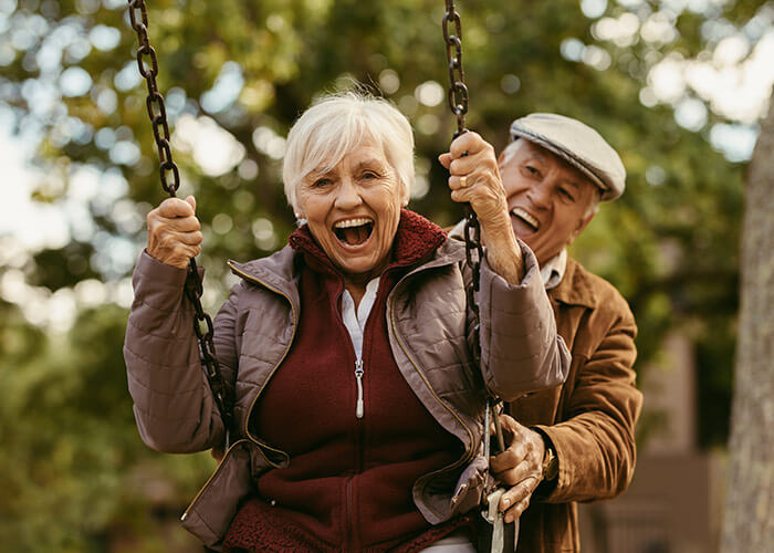 elderly man pushing wife on swing
