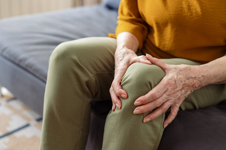 Person holding knee due to osteoarthritis joint pain in Houston & Texas.