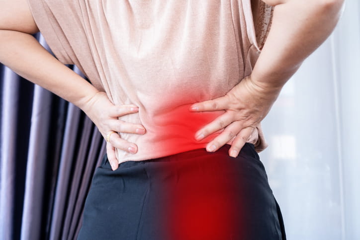 Person holding lower back due to sciatica pain radiating to the lower body in Dallas & Texas